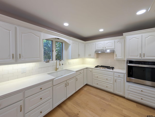 2505 Merry Ln, Tyler, TX 75701 - kitchen with stainless steel appliances, under cabinet range hood, white cabinets, light wood-style floors, and recessed lighting