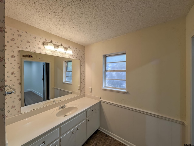 2505 Merry Ln, Tyler, TX 75701 - bathroom featuring a wainscoted wall, vanity, a textured ceiling, and wallpapered walls