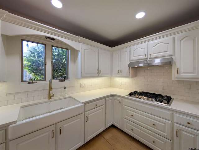 2505 Merry Ln, Tyler, TX 75701 - kitchen featuring stainless steel gas stovetop, under cabinet range hood, white cabinets, backsplash, and light countertops