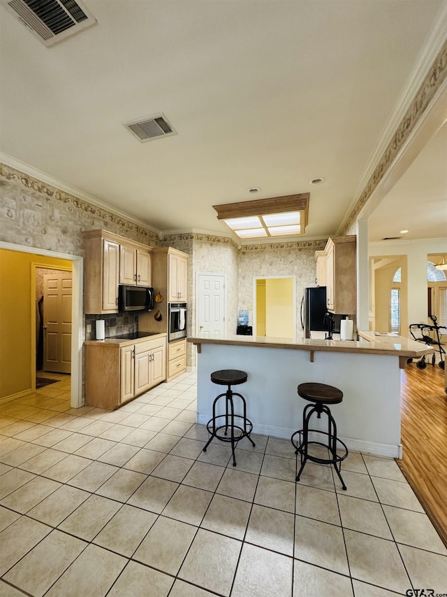 kitchen featuring light tile patterned floors, light brown cabinets, ornamental molding, a kitchen breakfast bar, and kitchen peninsula