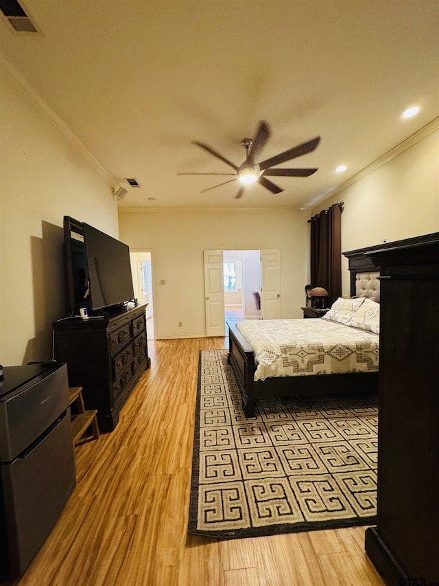 bedroom with crown molding, ceiling fan, and light hardwood / wood-style flooring