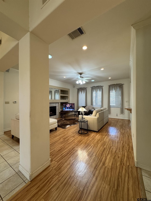 living room with ceiling fan, a tile fireplace, and light hardwood / wood-style flooring