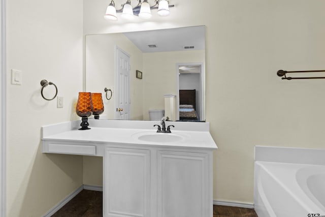 bathroom with vanity, a tub to relax in, and toilet