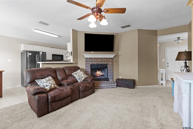 living room with a brick fireplace, ceiling fan, and light carpet