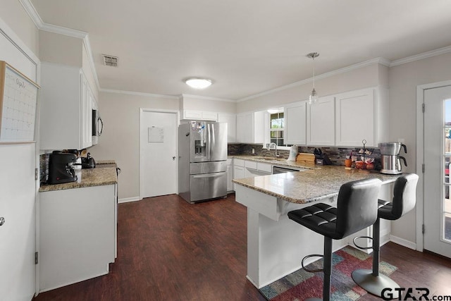 kitchen featuring dark wood-style floors, stainless steel appliances, visible vents, decorative backsplash, and a peninsula