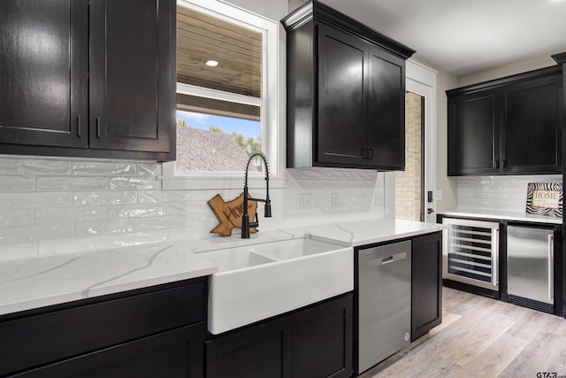 kitchen featuring sink, tasteful backsplash, light hardwood / wood-style floors, beverage cooler, and stainless steel appliances