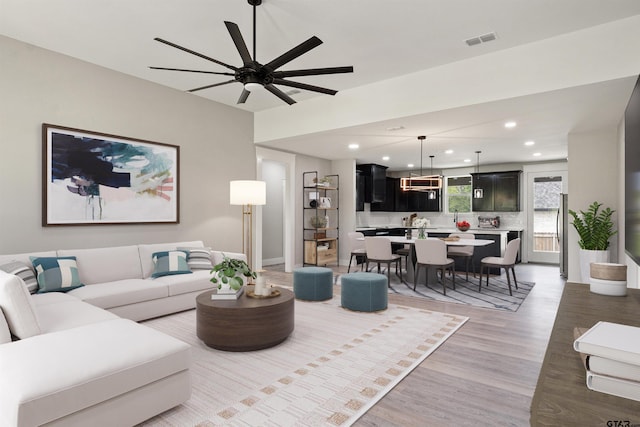 living room with light hardwood / wood-style flooring and ceiling fan