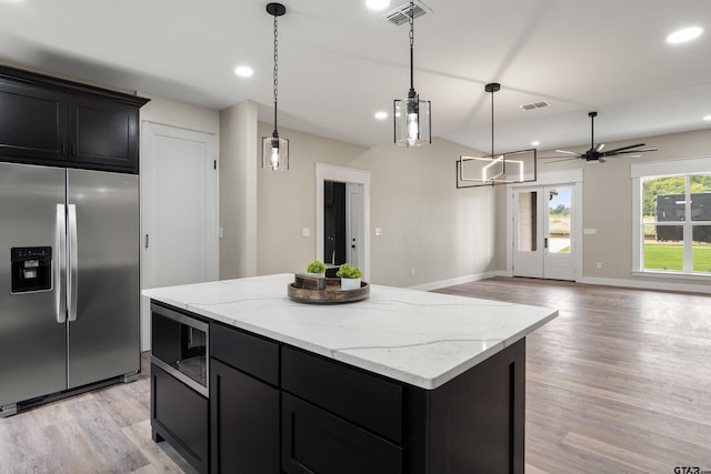 kitchen with built in microwave, hanging light fixtures, light wood-type flooring, stainless steel fridge with ice dispenser, and a kitchen island