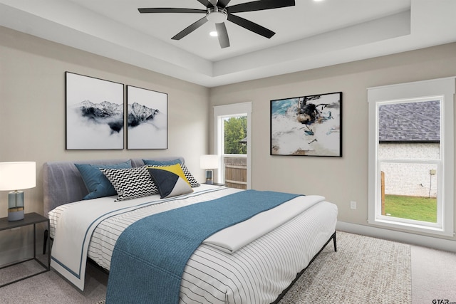 carpeted bedroom with ceiling fan and a raised ceiling