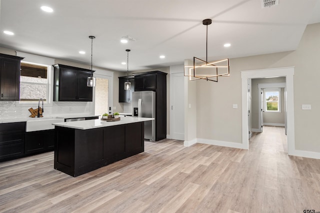 kitchen featuring sink, a kitchen island, pendant lighting, and stainless steel refrigerator with ice dispenser