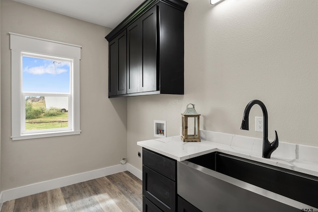 clothes washing area featuring cabinets, electric dryer hookup, sink, hookup for a washing machine, and light hardwood / wood-style flooring