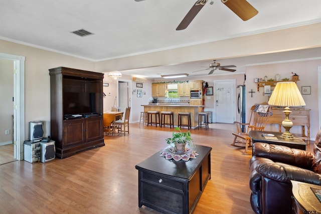 living room featuring ceiling fan, ornamental molding, and light hardwood / wood-style flooring