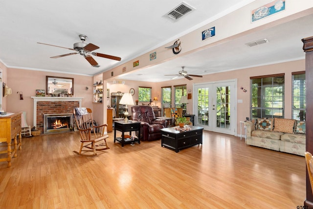 living room featuring a brick fireplace, hardwood / wood-style floors, ornamental molding, and ceiling fan