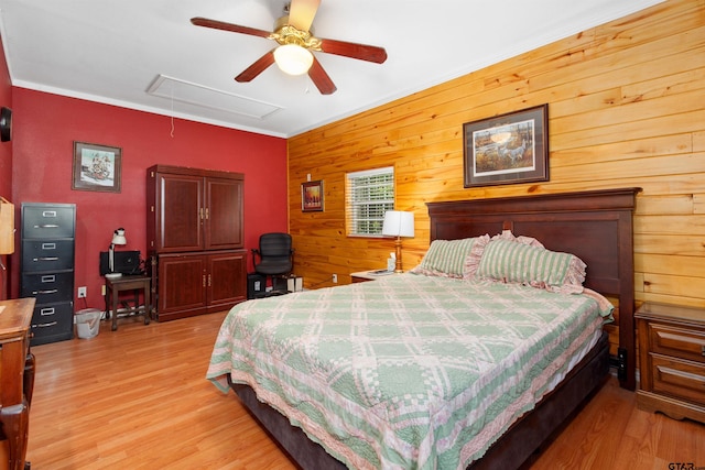 bedroom with wood walls, ceiling fan, light wood-type flooring, and crown molding