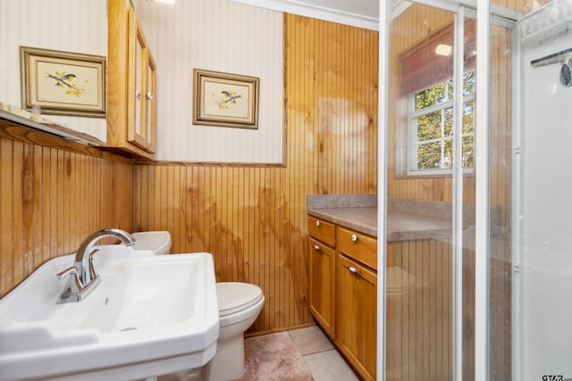 bathroom featuring tile patterned flooring, sink, wooden walls, and toilet