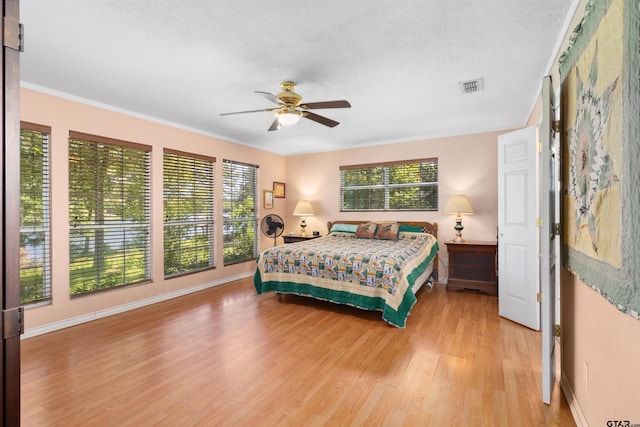 bedroom with ornamental molding, light hardwood / wood-style floors, multiple windows, and ceiling fan