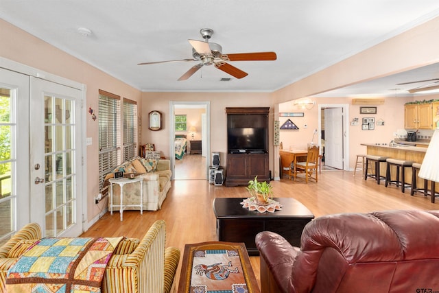 living room featuring ceiling fan, light wood-type flooring, french doors, and ornamental molding