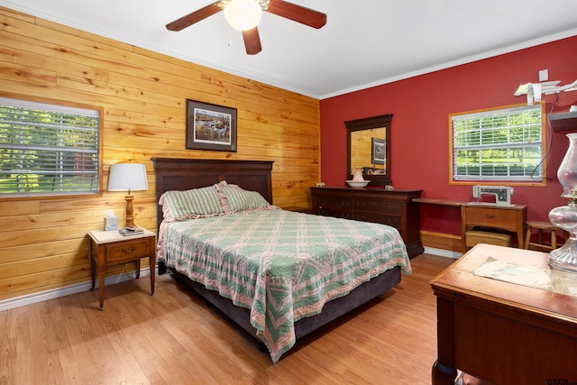 bedroom featuring ornamental molding, light hardwood / wood-style flooring, wood walls, and ceiling fan