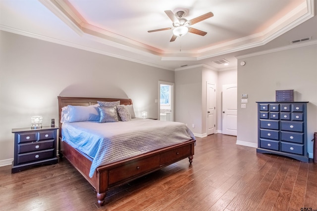 bedroom with crown molding, dark wood-type flooring, a raised ceiling, and ceiling fan