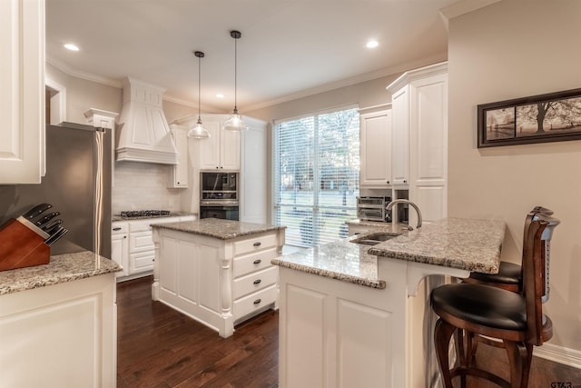 kitchen featuring white cabinetry, hanging light fixtures, light stone countertops, and a center island