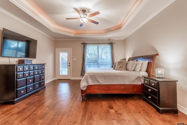 bedroom featuring a tray ceiling, ornamental molding, access to exterior, ceiling fan, and light hardwood / wood-style floors