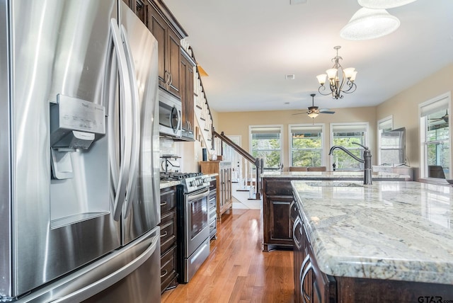 kitchen with sink, dark brown cabinets, appliances with stainless steel finishes, a healthy amount of sunlight, and a kitchen island with sink