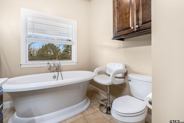 bathroom with a washtub, tile patterned floors, and toilet