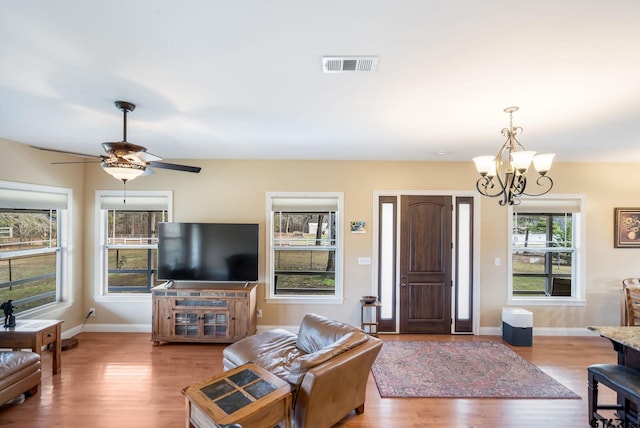 living room featuring ceiling fan with notable chandelier and light wood-type flooring