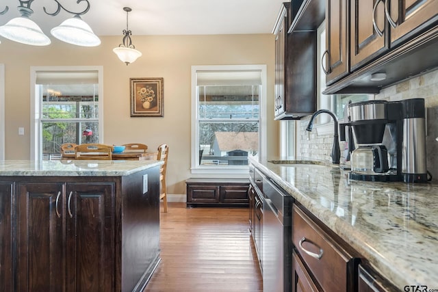 kitchen featuring pendant lighting, sink, dark brown cabinets, and light stone countertops