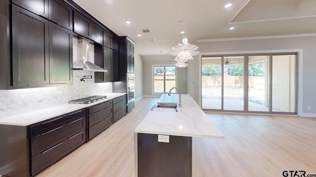 19346 Aida Dr, Flint, TX 75762 - kitchen featuring wall chimney exhaust hood, stainless steel appliances, light wood-type flooring, an island with sink, and backsplash