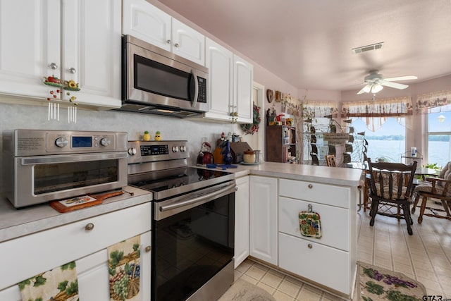 15541 Precidio Cir, Malakoff, TX 75148 - kitchen with stainless steel appliances, light tile patterned flooring, white cabinets, and a peninsula