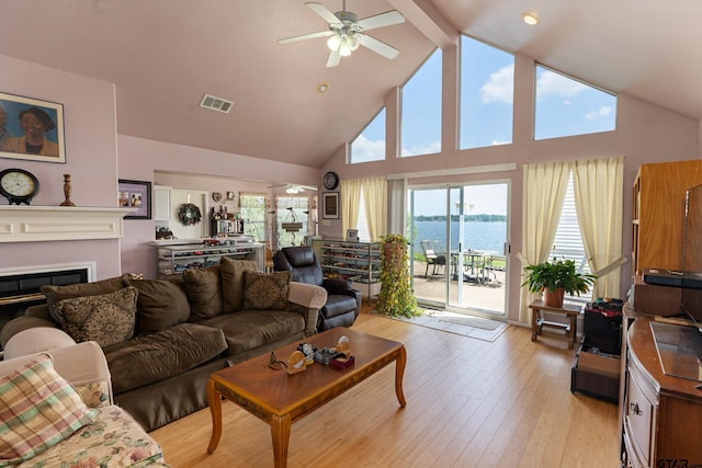 15541 Precidio Cir, Malakoff, TX 75148 - living area with a ceiling fan, high vaulted ceiling, a water view, light wood-type flooring, and a glass covered fireplace