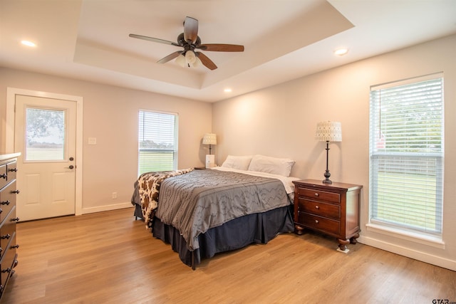 bedroom featuring a tray ceiling, ceiling fan, and light hardwood / wood-style floors