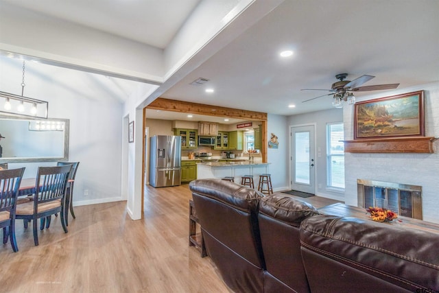 living room with a fireplace, light hardwood / wood-style floors, and ceiling fan