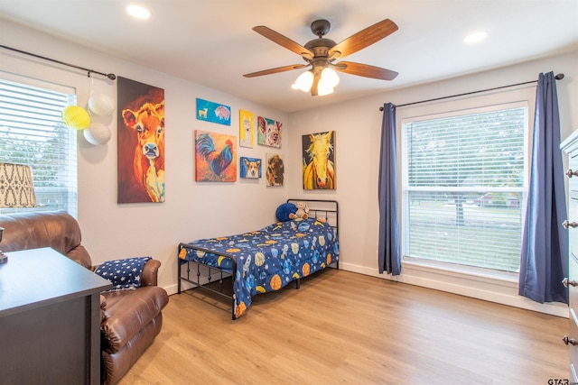 bedroom with ceiling fan, light wood-type flooring, and multiple windows