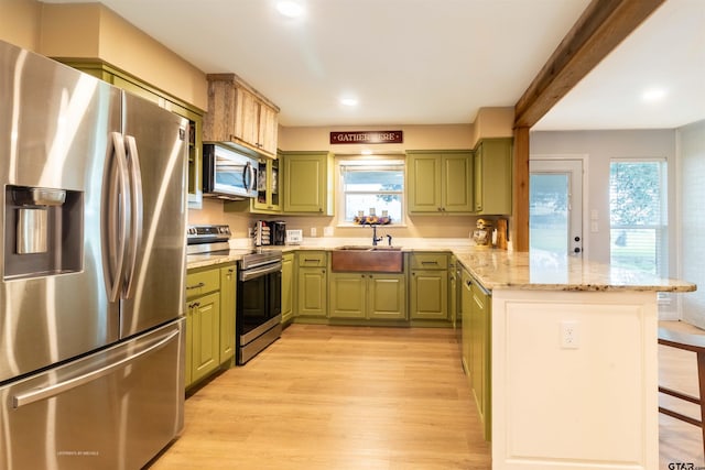 kitchen featuring green cabinets, light hardwood / wood-style flooring, kitchen peninsula, plenty of natural light, and appliances with stainless steel finishes