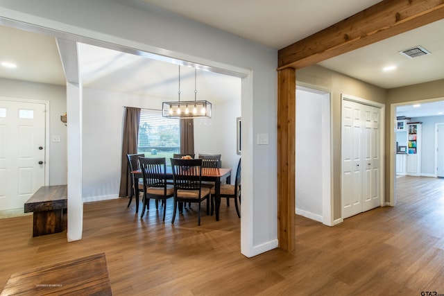 dining room with a chandelier, wood-type flooring, and beam ceiling