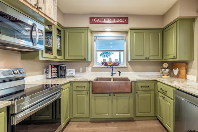 kitchen with light stone countertops, sink, green cabinetry, and appliances with stainless steel finishes