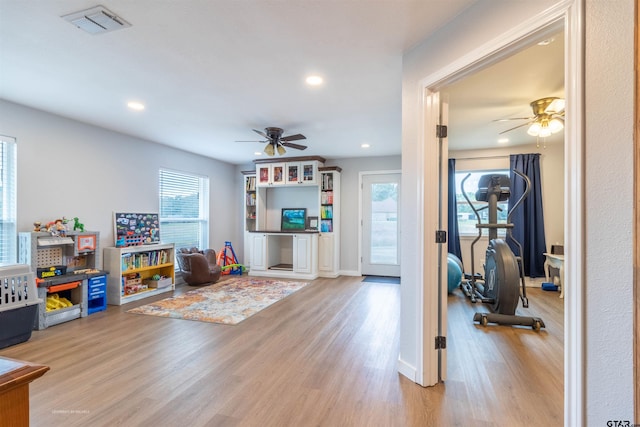 workout area featuring ceiling fan and light hardwood / wood-style flooring