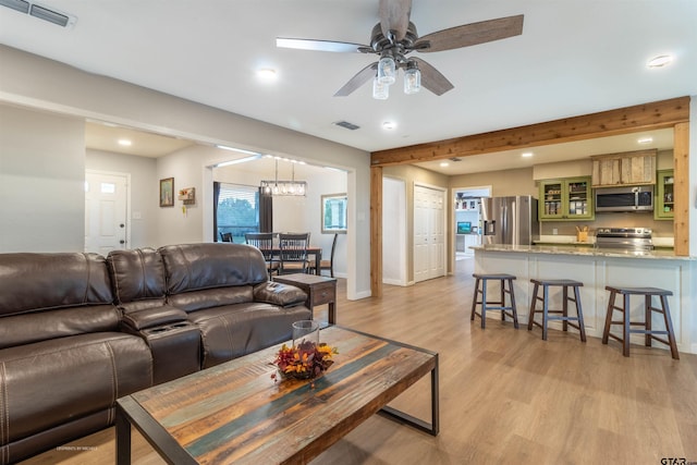 living room featuring ceiling fan with notable chandelier and light hardwood / wood-style floors