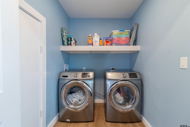 clothes washing area with washer and clothes dryer and hardwood / wood-style floors