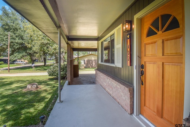 view of exterior entry with a porch and a lawn