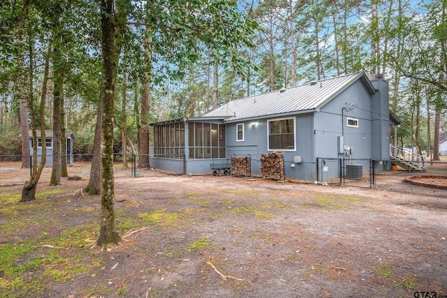 back of house featuring cooling unit, a sunroom, fence, and metal roof