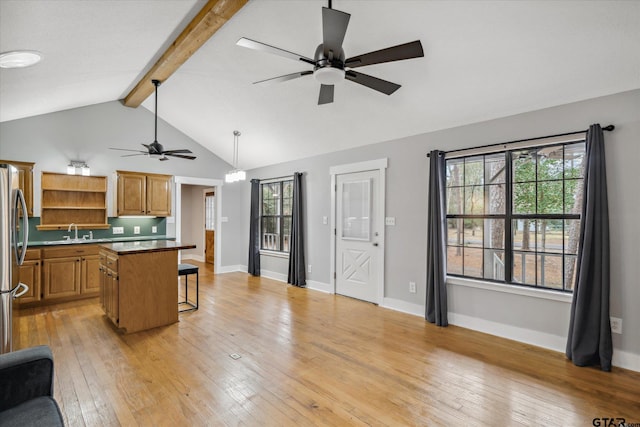 kitchen featuring light wood finished floors, open shelves, a sink, beamed ceiling, and a kitchen bar