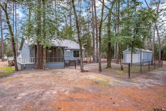 view of yard featuring a garage, an outbuilding, a sunroom, and fence