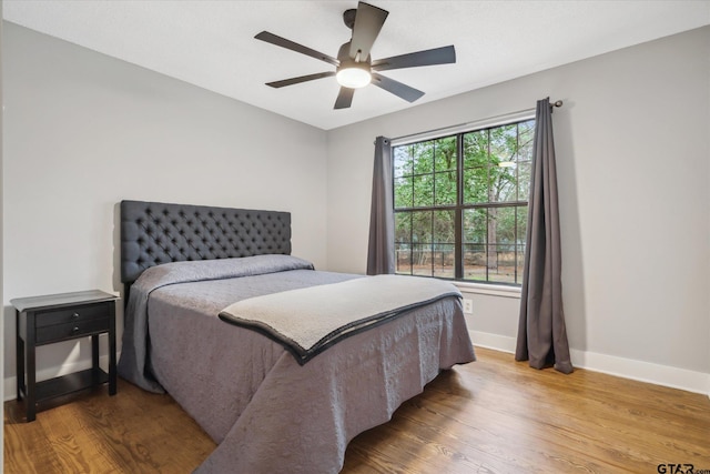 bedroom with wood finished floors, a ceiling fan, and baseboards