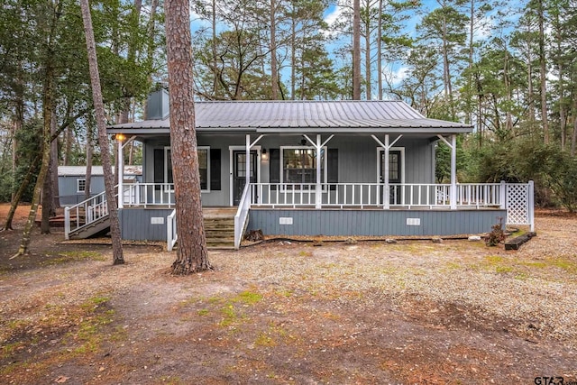 view of front of property with covered porch, stairs, and metal roof