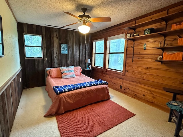 bedroom with a textured ceiling, ceiling fan, and wood walls