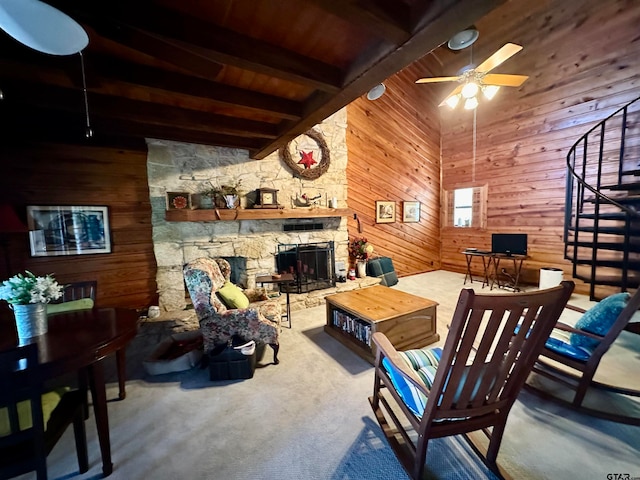 carpeted living room with ceiling fan, wooden ceiling, beamed ceiling, wood walls, and a fireplace