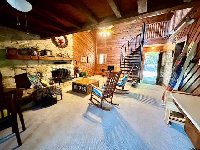 living room with wood ceiling, wooden walls, beam ceiling, carpet floors, and a stone fireplace